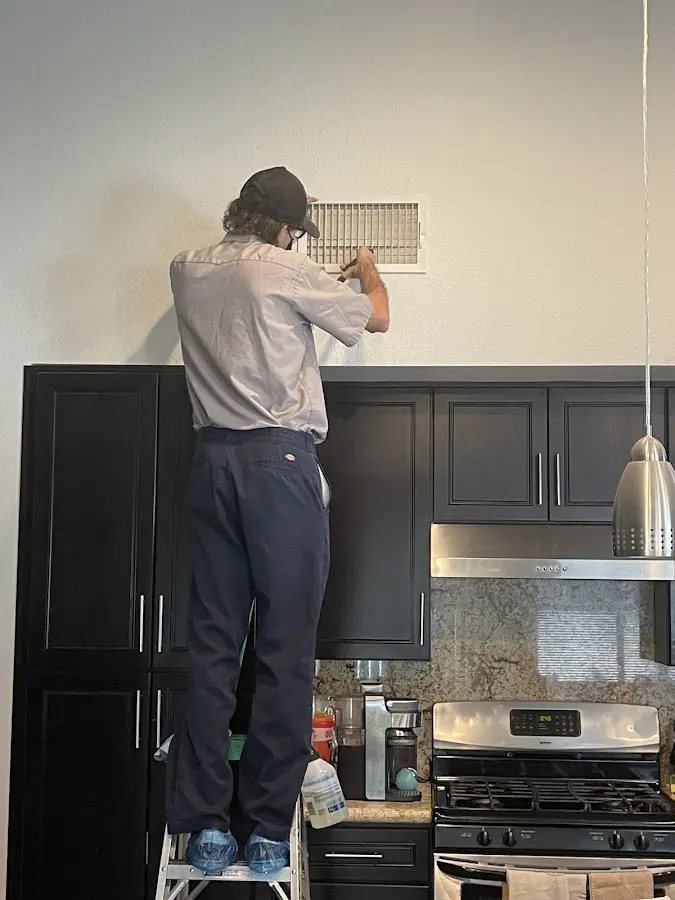 Technician inspecting an air vent during HVAC service in Trotwood